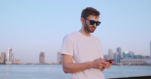 The Man Dials the Number on the Phone and Talks on the Background of the Panorama of Dubai
