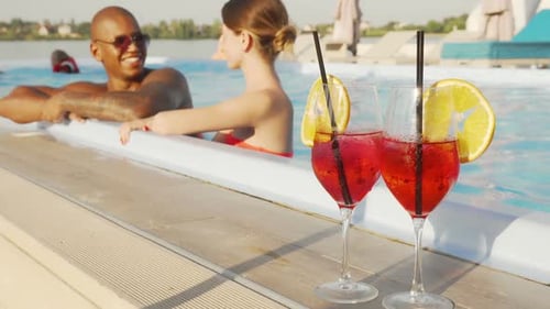 Young Couple Talking While Resting in the Swimming Pool Together