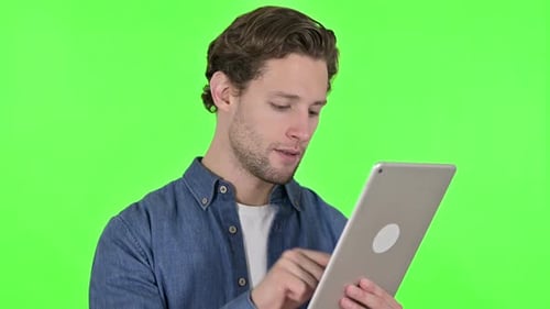 Focused Young Man Using Digital Tablet on Green Chroma Key