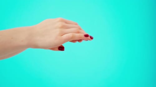 Female Hands Applying Hand Creme Against Blue Background