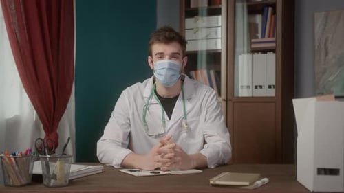 Young Doctor Wearing Mask Sitting at Desk