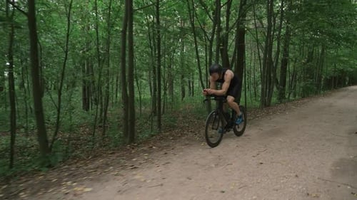 Mann, Triathlet, fährt Fahrrad, Radprofi fährt auf einer Waldstraße, Vorbereitung für Wettkämpfe und