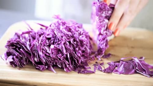 Cutting fresh red cabbage on a wood cutting board.