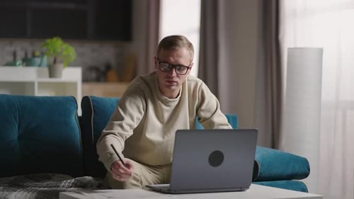 Young Man Works on Laptop in Home