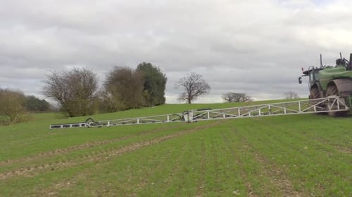 Tractor Sprays Pesticides on Crops in Green Field
