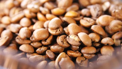 Makro-Kaffeebohnen in Zeitlupe fallen auf Haufen im Behälter