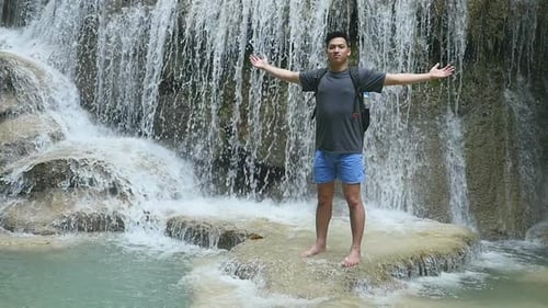 Young Man Enjoying Tropical Waterfall Scenery