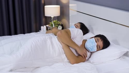 Couple Sleeping in Masks in Bed at Night