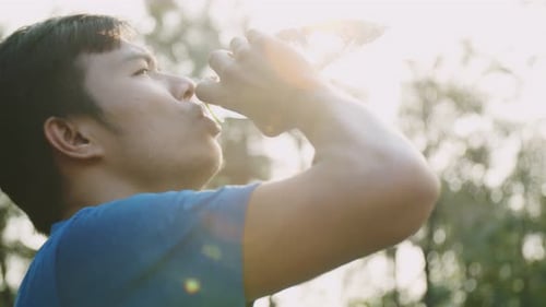 Young Adult Drinking Water Outside in Nature