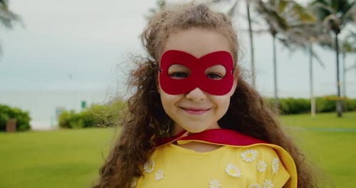 Young Girl in Superhero Costume Smiling on Lawn