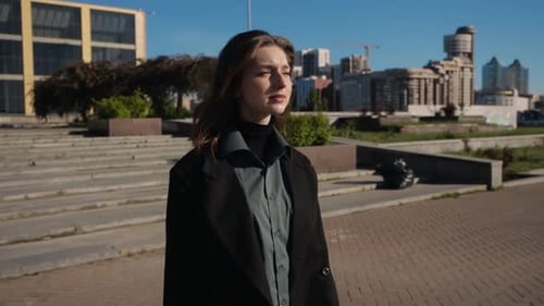 Beautiful Natural Brunette with Dreamy Look Walks Through Square on a Clear Day