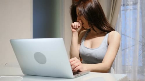 Woman Coughing While Working on Laptop at Home