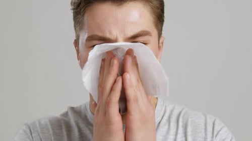 Young Man Blowing His Nose with a Tissue