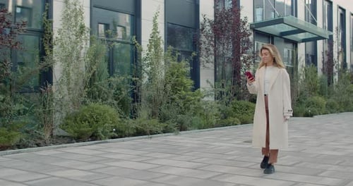 Woman Walks and Uses Mobile Phone on Street