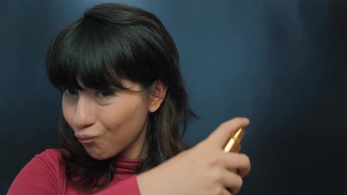 Woman Sprays Herself with Cosmetic Product Close Up