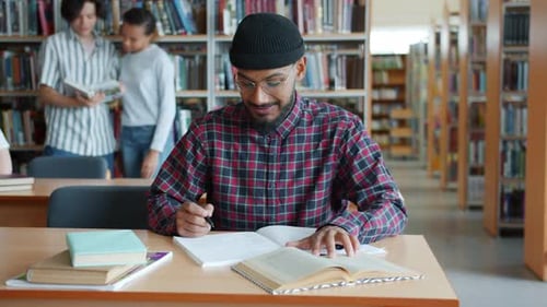African American Student Learning in Library Reading Writing Sitting at Desk