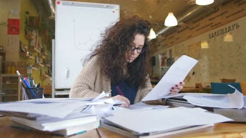 Tired Businesswoman in the Office with Stack of Papers
