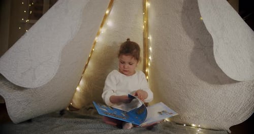 Little Girl Reads in Cozy Blanket Fort