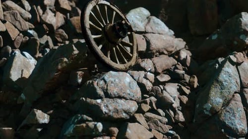 Aged Wooden Cart Wheel Resting on Rough Stone Surface