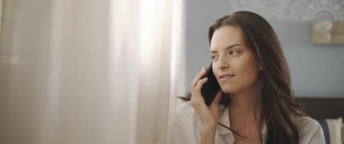 Close up of a woman talking to someone on the phone, near the window