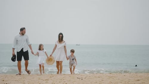 Family Walks Hand-in-Hand Along Sandy Ocean Beach