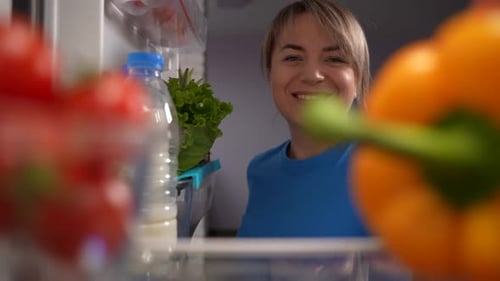 Smiling Woman Taking Vegetables from the Refrigerator