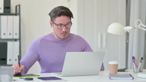 Man Working With Tablet and Laptop at Desk