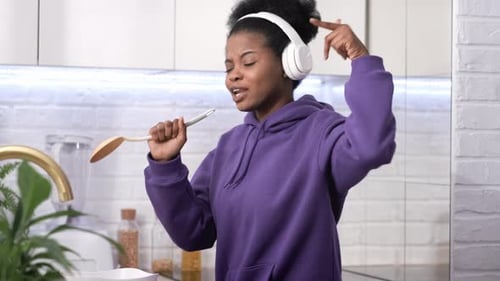 Woman Dancing and Singing with Spoon in Kitchen