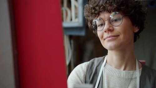 Portrait of Attractive Female Artist Painting Picture Working Alone in Modern Studio