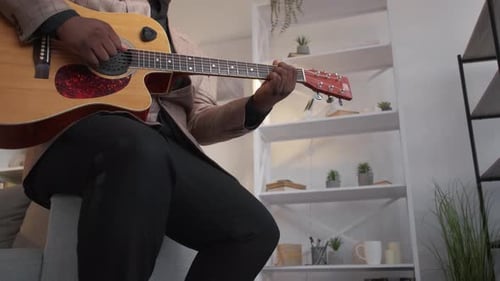 Man Playing Acoustic Guitar Indoors at Home