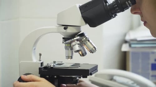 Woman Doctor Looks in a Microscope