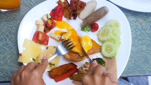 Cutting Open Egg Benedict with Breakfast Buffet