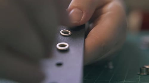 Hands Adding Rivets to a Piece of Leather
