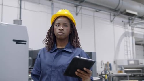 Black Female Factory Engineer with Dreads Consulting Tablet