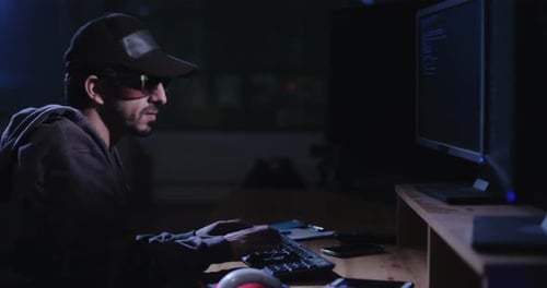 Computerhacker sitzt in einem dunklen Raum und hackt Sicherheitssysteme