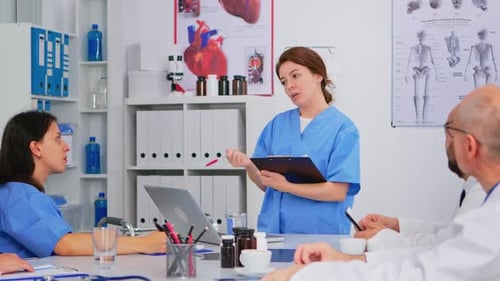 Team of Doctors Discussing Diagnosis Sitting at Table in Clinic