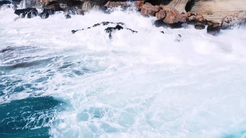 Aerial View of Waves Break on Rocks in a Blue Ocean Sea Waves on Beautiful Beach Bird's Eye View of