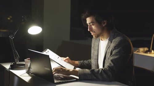 Ein konzentrierter Büroangestellter überprüft einen Geschäftsbericht, ein Mann hatte keine Zeit, die Arbeit pünktlich zu beenden und