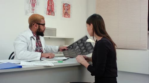 Doctor Explains Scan Results to Woman in Clinic