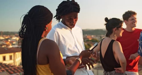 Young Adults Laughing on a Rooftop at Sunset