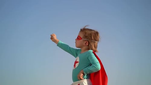 Child Posing as Superhero Against Blue Sky