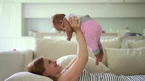 Woman Holding Infant Child Up on Couch