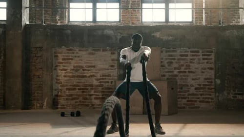 Entrenamiento físico. Deportista haciendo ejercicio con la cuerda de batalla en el gimnasio