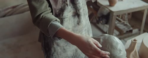 Female Sculptor Working on Clay Head in Studio