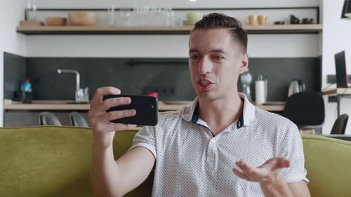 Young man video calling on smartphone in apartment