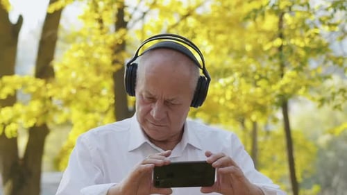 Senior Man Watching Video on Phone in Park