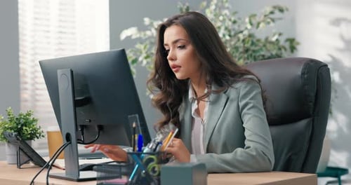 Beautiful Busy Businesswoman Sits at Desk in Front of Computer in Office Has Technical Problems with