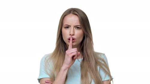 Porträt einer seriösen blonden Frau, die den Zeigefinger auf den Lippen hält und strikt darum bittet, still zu bleiben