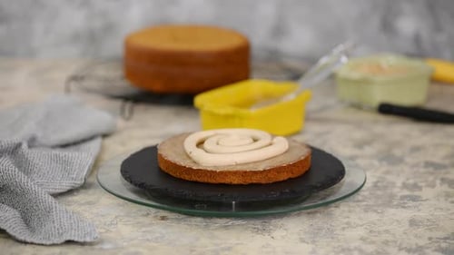 Girl making a cake in a bakery. Baker squeezes cream onto a cake layer