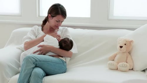 Mother breast feeding baby on sofa